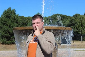 Mike picking his nose in front of a pretty fountain.